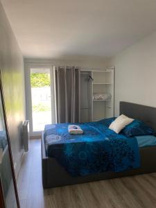 una camera con un letto blu e una finestra di Agréable chambre a Menucourt