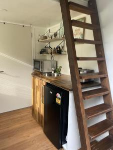 a kitchen with a black refrigerator and a ladder at Tiny House in the Bush - a minute from town centre in Raetihi