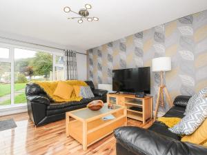 a living room with black leather furniture and a flat screen tv at 6 Manorcombe Bungalows in Callington