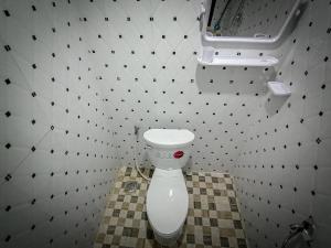 łazienka z toaletą w wyłożonej kafelkami ścianie w obiekcie Ching Ching Guest House w mieście Preăh Sihanŭk