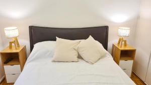 ein Bett mit weißen Laken und zwei Nachttischen in der Unterkunft Alquiler temporario en Vicente López in Vicente López