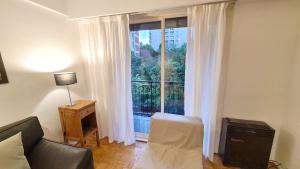 ein Wohnzimmer mit Couch und großem Fenster in der Unterkunft Alquiler temporario en Vicente López in Vicente López