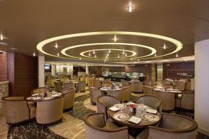 a restaurant with tables and chairs and a circular ceiling at Bizz The Hotel in Rajkot