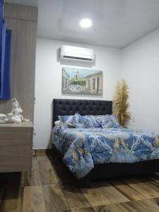 a bedroom with a bed with a blue comforter at HOTEL REAL DEL VALLE in Valledupar