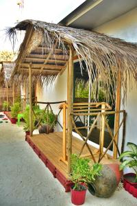 een kleine hut met een rieten dak en een aantal planten bij Maafushi View in Maafushi