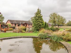 a garden with a pond in front of a house at Molls Cottage in Nantwich