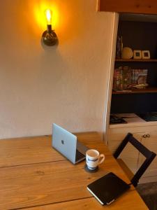 um computador portátil numa mesa de madeira com uma chávena de café em The Cottage St Kew em Port Isaac