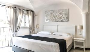 a white bedroom with a bed and a large window at Albergo Diffuso Mannois in Orosei