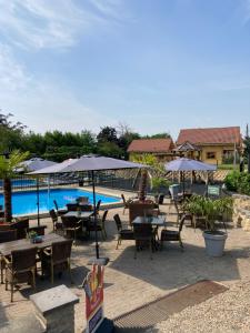 een patio met tafels en parasols naast een zwembad bij Family Woodlodge High Chaparral in Oorsbeek