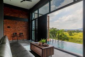 a living room with a couch and a large window at Two Villa by StayVista with Infinity Pool, Farm & Mountain Views, Modern Interiors in Karjat