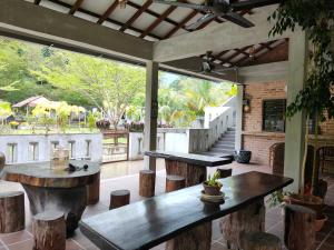 a patio with two tables and stools and trees at Pangkor Nature View House in Pangkor