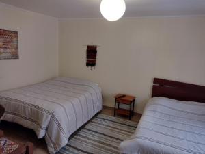 a bedroom with two beds and a rug at Hostal CacTus in Coquimbo