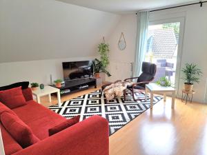 sala de estar con sofá rojo y sillas en Ferienwohnung Rosengarten, en Rosengarten