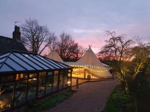 a marquee with a tent and a building with lights at Rylands Farm Guest House in Wilmslow