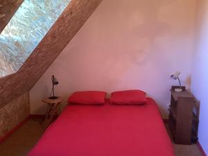 Pleasant cottage in Le Veurdre with private garden في Le Veurdre: غرفة نوم بسرير احمر في العلية
