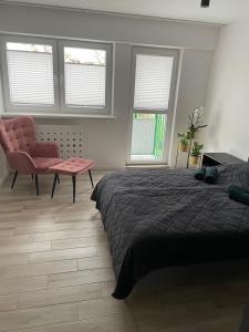 a bedroom with a bed and a chair and windows at Brzostek Apartamenty 1 in Warsaw