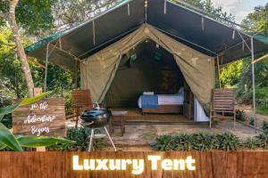 Zelt mit einem Bett, Stühlen und einem Grill in der Unterkunft Sky Island Resort in Ponta Malangane