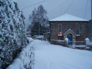 una casa cubierta de nieve con un patio cubierto de nieve en Rainforest Chapel, en Longney