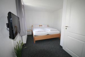 a small bedroom with a bed and a flat screen tv at Lüttje Gesine Lüttje Gesine in Norderney +3 photos