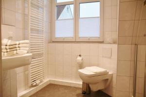 a bathroom with a toilet and a sink and a window at Lüttje Gesine Lüttje Gesine in Norderney