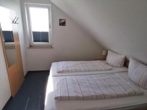 two beds in a white room with a window at Ferienhaus Rosenboom Rosenboom 01 in Norderney