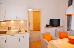 a kitchen with white cabinets and a kitchen with orange chairs at Ferienhaus Pauls Ferienhaus Pauls, Whg 03 in Norderney