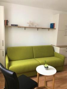 un soggiorno con divano verde e tavolo di Lüttje Huus Lüttje Huus 01 a Norderney