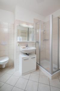 een witte badkamer met een wastafel en een douche bij Lüttje Huus Lüttje Huus 02 in Norderney