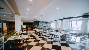 a restaurant with tables and chairs on a checkered floor at King's Hotel Nagoya Batam in Nagoya