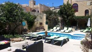 a pool with chaise lounge chairs and a group ofitures at Charming B&B Dar Ta Zeppi in Qala