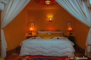 a bedroom with a large white bed with two lamps at Dar Amoudou in Ouarzazate
