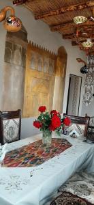 a table with a vase of red flowers on it at Guest House Art Postindoz in Khiva