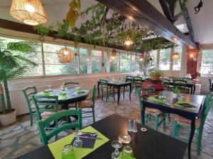 un restaurante con mesas, sillas y ventanas en Auberge du botaniste en Boissières