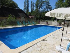 a swimming pool with an umbrella and chairs at Auberge du botaniste in Boissières