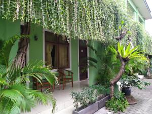 a green building with a table and chairs and plants at PURNAMA HOUSE KUTA in Kuta