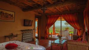 a bedroom with a bed and a table and a balcony at Dar Amoudou in Ouarzazate