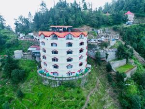 a large white building with a red roof on a hill at Kufri Pacific Resort in Mundaghat 