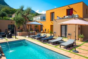 a pool with chairs and umbrellas next to a building at A CASA DI JO in Calenzana