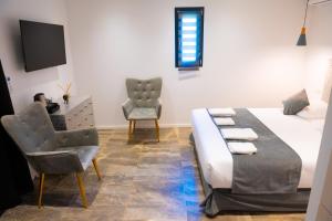 a bedroom with a bed and two chairs and a tv at A CASA DI JO in Calenzana