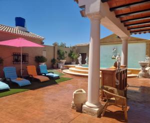 a patio with chairs and an umbrella and a fountain at LA FUENTE ROMANA in Campo-Nubes