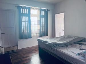 Cama en habitación con ventanas en Norbus Homestay en Darjeeling