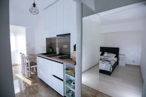 a kitchen with white cabinets and a bed in a room at Apartament CENTRAL in Târgu Jiu