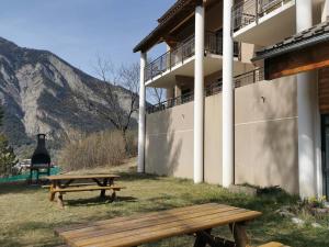 dwa stoły piknikowe przed budynkiem w obiekcie Appartement 6 pers avec piscine et sauna à Jausiers - Terrasse exposée sud - Proche Barcelonnette - FR-1-165B-14 w mieście Jausiers +1 zdjęcie