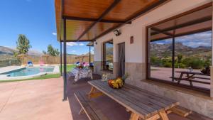 un patio con una mesa de picnic de madera y una piscina en Casa Rural Tajo de Gómer Riogordo by Ruralidays, en Ríogordo