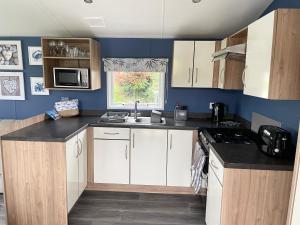 una pequeña cocina con armarios blancos y fregadero en Newquay Bay Resort - Sea Breeze 61 en Newquay