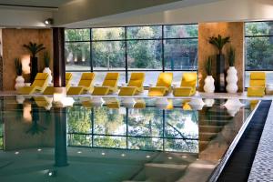 a swimming pool with yellow chairs in a building at Thalazur Arcachon - Hôtel & Spa in Arcachon