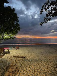 two chairs sitting on a beach at sunset at Sun Smile Beach Koh Jum in Ko Jum
