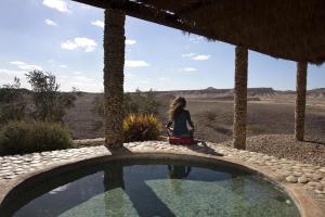 a woman sitting next to a swimming pool in a resort at Arava Land in Zuqim