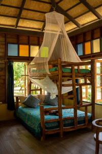 a bedroom with a wooden bed with a mosquito net at Monkey Mansion - Jungalows & Tours in Khao Sok