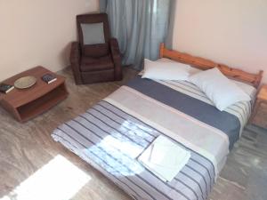 a bedroom with a bed and a chair and a table at Oropos Memories House in Skála Oropoú